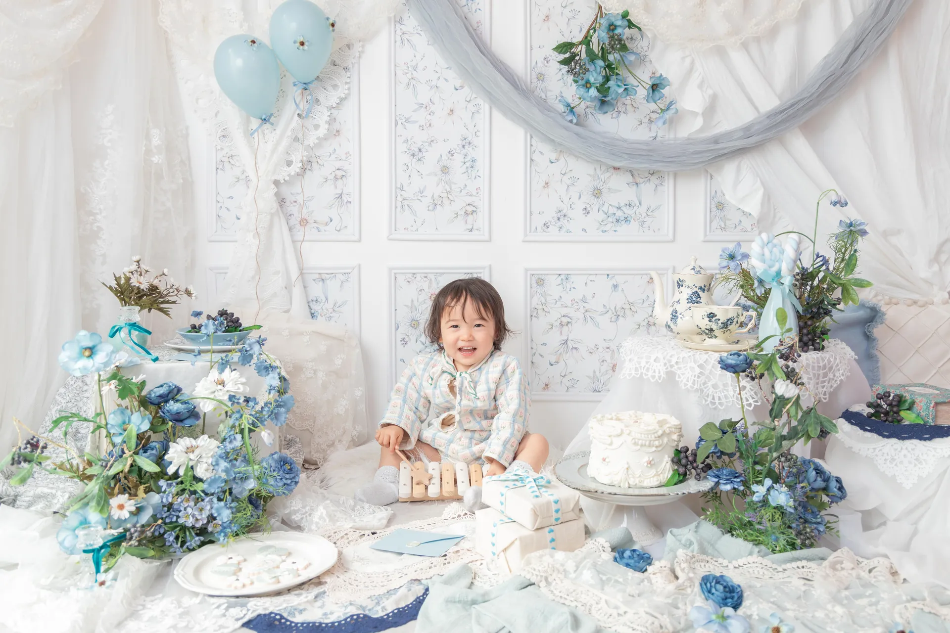青い花と白いケーキのセットで、子どもが笑っている写真