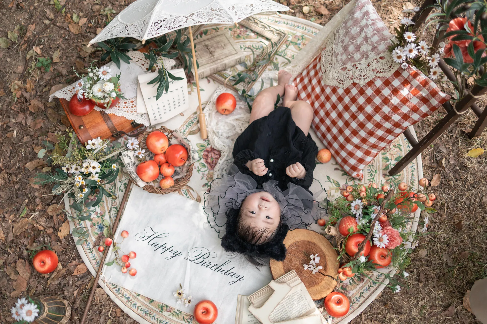 りんごやレースを並べたピクニックのセットで、寝転ぶ子どもの写真